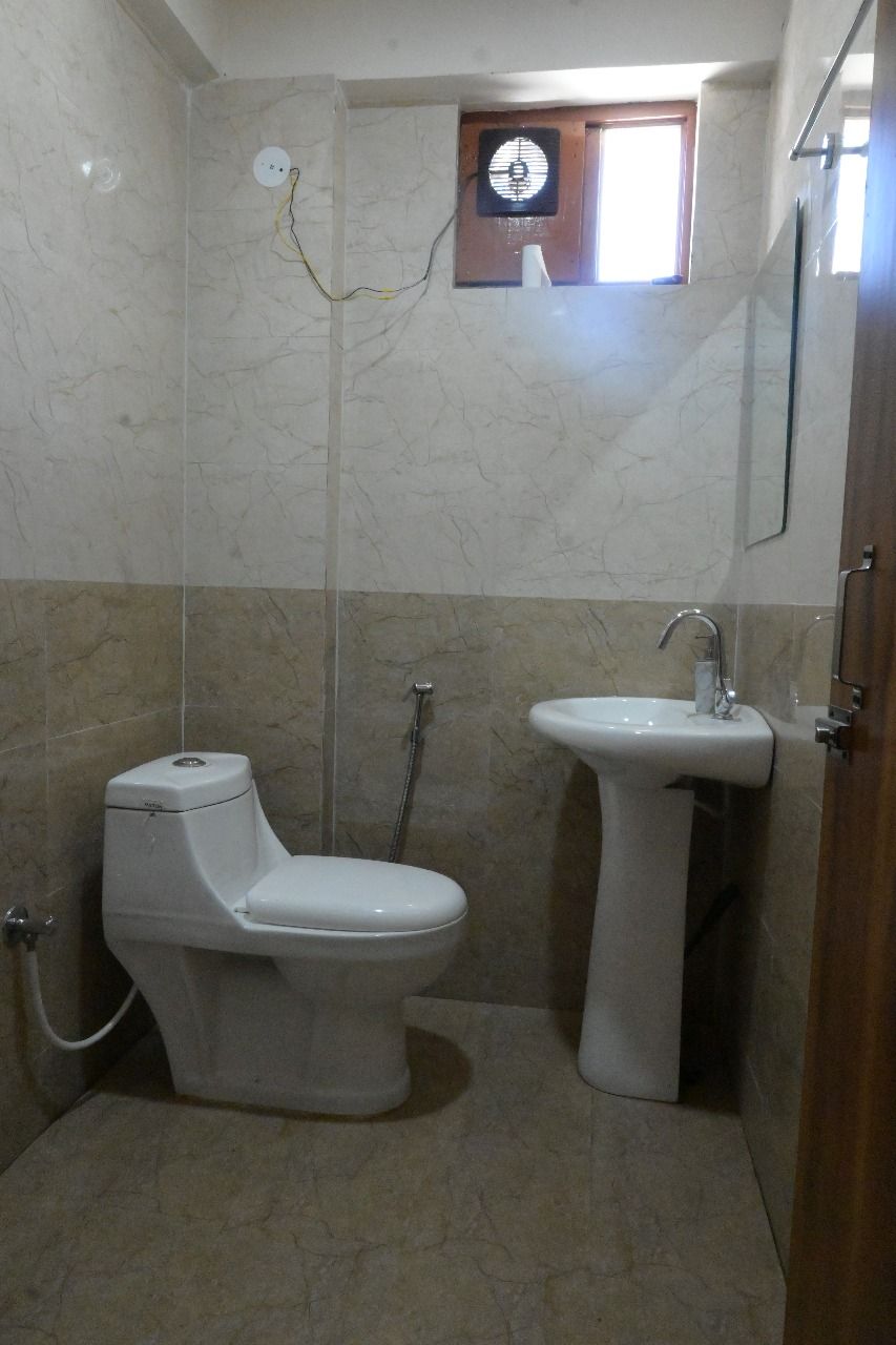 A small bathroom with a toilet, sink, and shower.