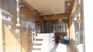 Uma área de recepção com decoração em madeira, um balcão de atendimento e um espaço de espera com mesa e cadeiras.