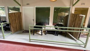 Una habitación con barandilla metálica verde, puerta blanca y separador de bambú.