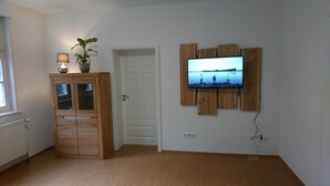 Ein Zimmer mit einem Holzschrank, einem an einer Holzplatte montierten Fernseher und einer Tür.