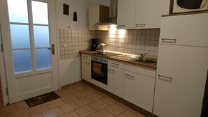 Eine Küche mit weißen Schränken, einem Herd, einer Spüle und einer Mikrowelle.