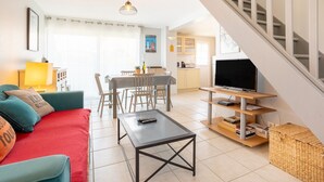 Un salon moderne avec un canapé, une table basse, un téléviseur et un escalier.