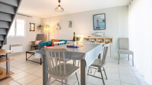 Un salon moderne avec un escalier, un coin repas et une cuisine.
