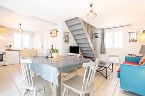Une cuisine moderne avec une table à manger, des chaises, un téléviseur et un escalier.
