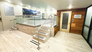 A modern hotel lobby with a glass railing staircase, a sauna sign, and a large poster on the wall. - Ski-In/Out Luxury / Central Location / King, Chef’s Kitchen / Park City Mtn Base (Park City)