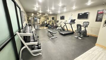 Un gimnasio con diversos equipos de ejercicio, incluyendo cintas de correr, bicicletas estáticas y máquinas de pesas.