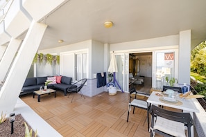A spacious balcony with a wooden floor, a sofa, a chair, and a dining table. - Luxury apartment with pool and panoramic views. (Santa Ursula)