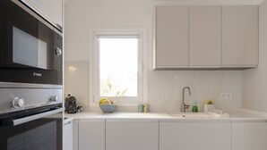 Eine moderne Küche mit weißen Schränken, einem Bosch-Ofen, einem Fenster mit Blick und einem Spülbecken mit Armatur.