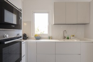 A modern kitchen with white cabinets, a Bosch oven, a window with a view, and a sink with a faucet. - Luxury apartment with pool and panoramic views. (Santa Ursula)