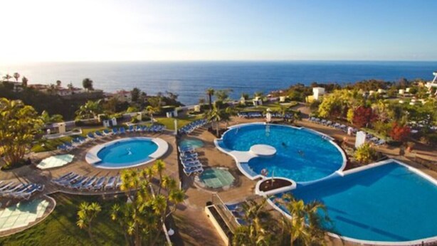 Ein Resort mit mehreren Swimmingpools, Liegestühlen und Blick auf den Ozean.