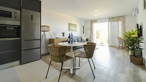 Eine moderne Küche mit Einbaugeräten, eine Essecke mit Korbstühlen und Blick zum Wohnzimmer.