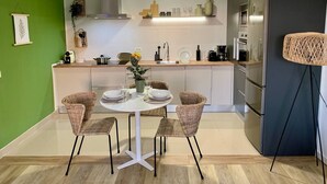 Eine moderne Küche mit Essbereich, ausgestattet mit einem runden Tisch, Korbstühlen und einem eingebauten Backofen.
