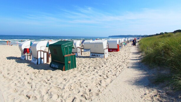 A beach with rows of beach chairs and umbrellas, a sandy path, and the ocean in the background. - Quietly situated vacation apartment - Ferienhaus Weingarten FeWo zum Fischer (Ostseebad Baabe)