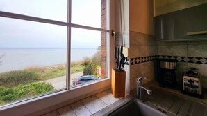 Una cocina con un ventanal que da a una playa y al mar.