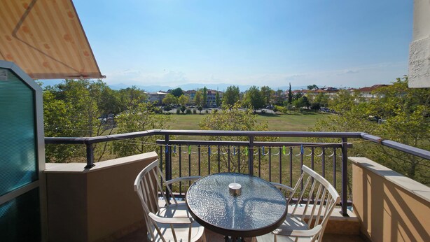 A balcony with a table and chairs, overlooking a residential area with houses and greenery. - Welcome to Double Room – Olympic Studios by SDR (Paralia)