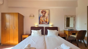 A hotel room with a bed, two nightstands, a wooden wardrobe, a desk with a chair, a mirror, and a painting on the wall. - Welcome to Double Room – Olympic Studios by SDR (Paralia)