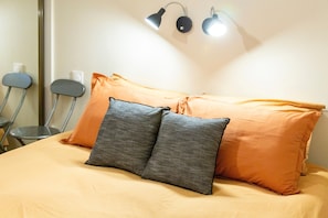 A bed with two pillows, a lamp, and a chair. - Renovated Apartment in the Heart of Pont-l’Abbé – River View, Close to the Ocean (Pont l'abbé)