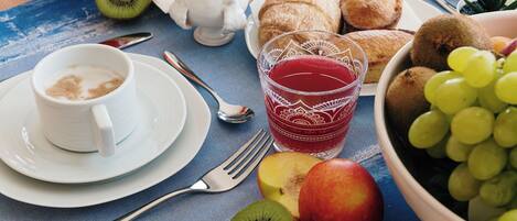 A breakfast setting with a cup of coffee, a glass of juice, a bowl of grapes, and various pastries on a table.