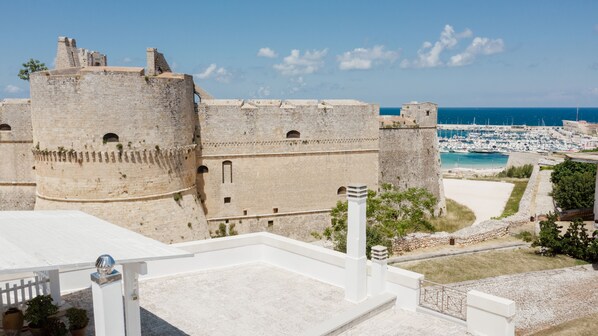 A historic stone fortress with a round tower, overlooking a marina with boats and a clear blue sky. - B&B Castello Otranto (Otranto)