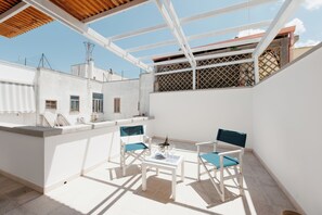 A rooftop terrace with a table and chairs, a bottle of champagne, and a view of the cityscape. - B&B Castello Otranto (Otranto)