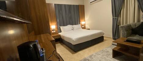 Quarto de hotel moderno com cama, mesas de cabeceira, escrivaninha e televisão.