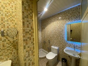 Een aparte badkuip en douche, een haardroger, handdoeken, zeep