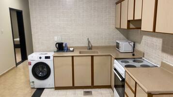A compact kitchen with a washing machine, microwave, and stove.