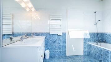 A modern bathroom with two sinks, a shower, and a toilet.