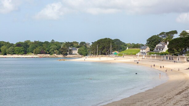 A beach with clear water, a sandy shore, and houses in the background. - Family Vacation Home in Bénodet (bénodet)