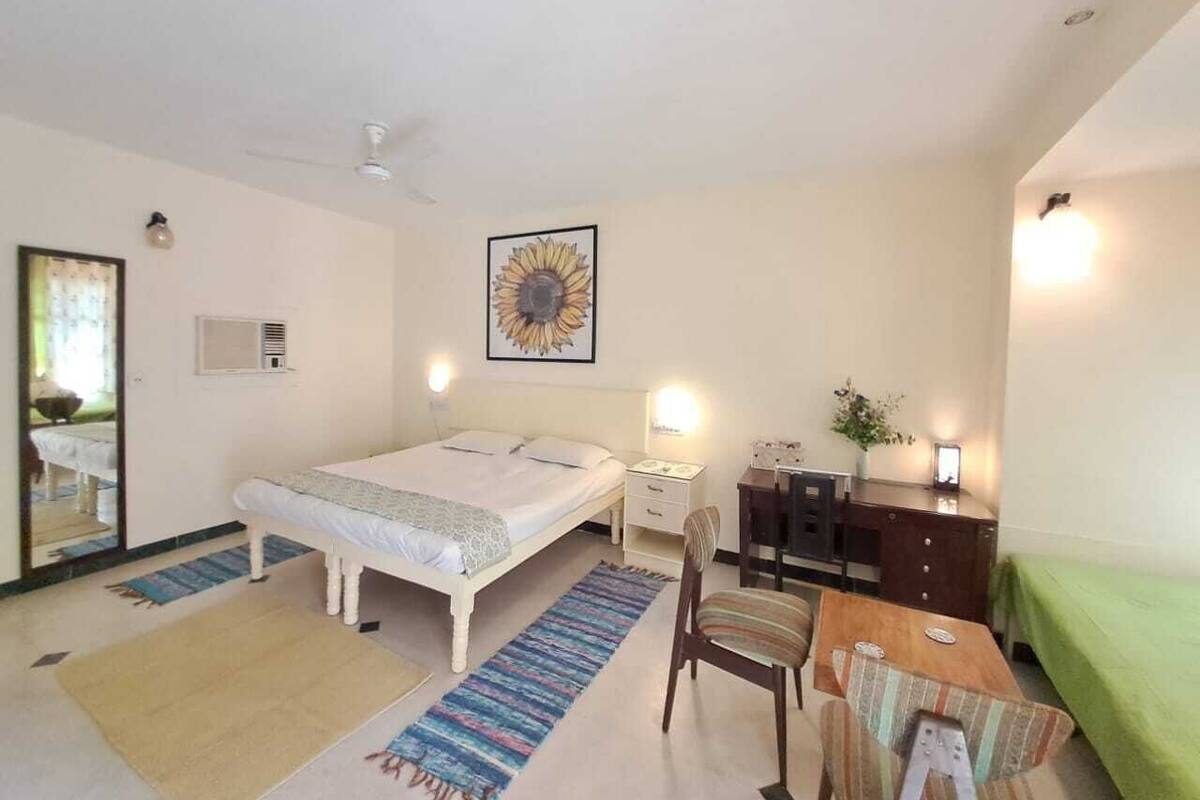 Ein Schlafzimmer mit Bett, Schreibtisch, Stuhl, Spiegel und einem Gemälde einer Sonnenblume.