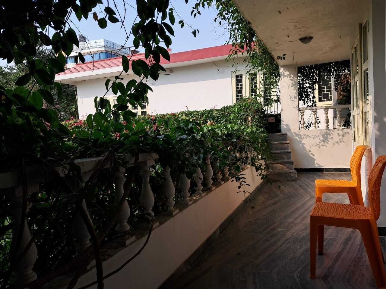Un balcon avec une chaise, un bâtiment blanc avec un toit rouge et un escalier menant à une porte.