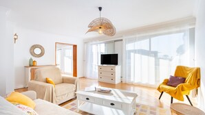 Un soggiorno moderno con divano, poltrona, tavolino e televisore.