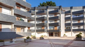 Un edificio residenziale a più piani con balconi, un cortile centrale e piante in vaso.