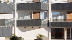Un edificio a più piani con balconi, ampie finestre e un ingresso con cancello.