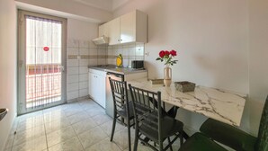 A compact kitchen with a dining area, featuring a sink, cabinets, and a vase with flowers. - ARETI Deluxe Two - Bedroom Suite n. 101 By SDR (Olimpiaki Akti)