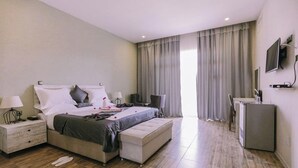 A modern bedroom with a bed, bedside tables, a desk, and a television.