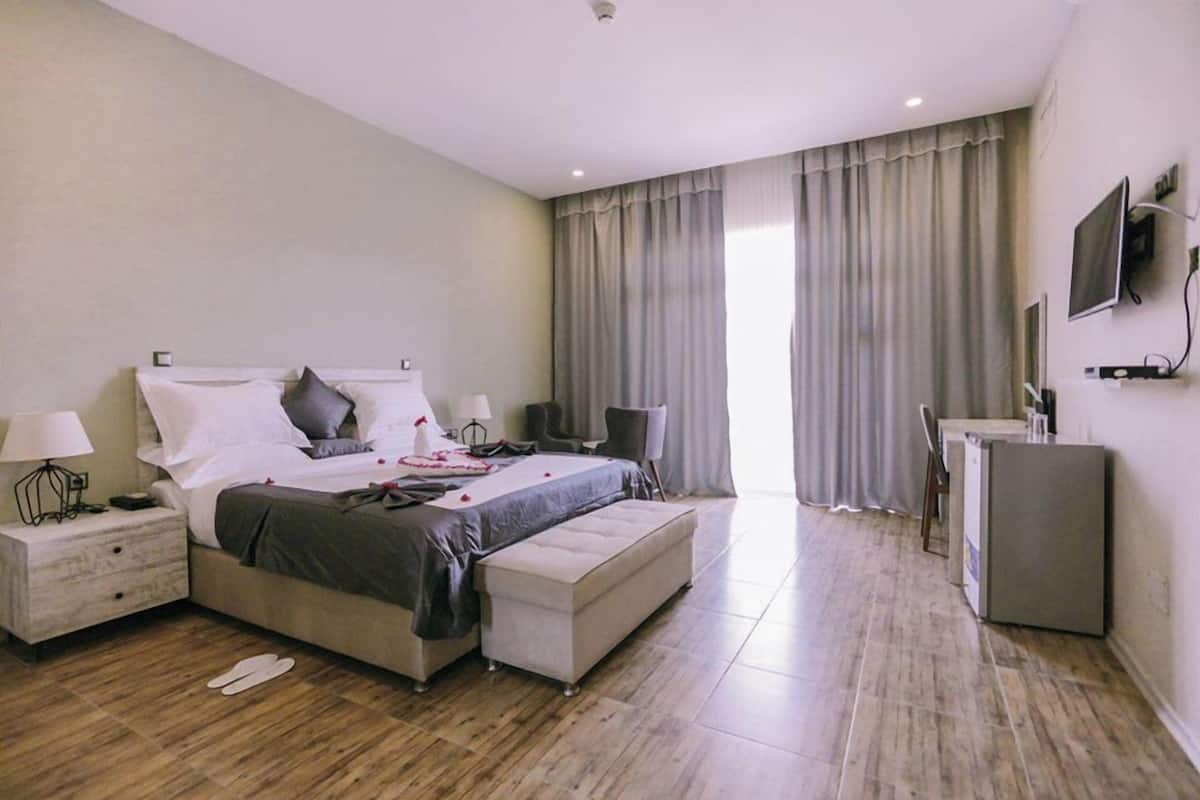 A modern bedroom with a bed, bedside tables, a desk, and a television.