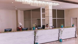 A reception desk with a modern design, featuring a white marble surface and blue planters with flowers.