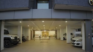 Una entrada de edificio moderno con un mostrador de recepción, un estacionamiento con varios autos y un piso de baldosas limpias.