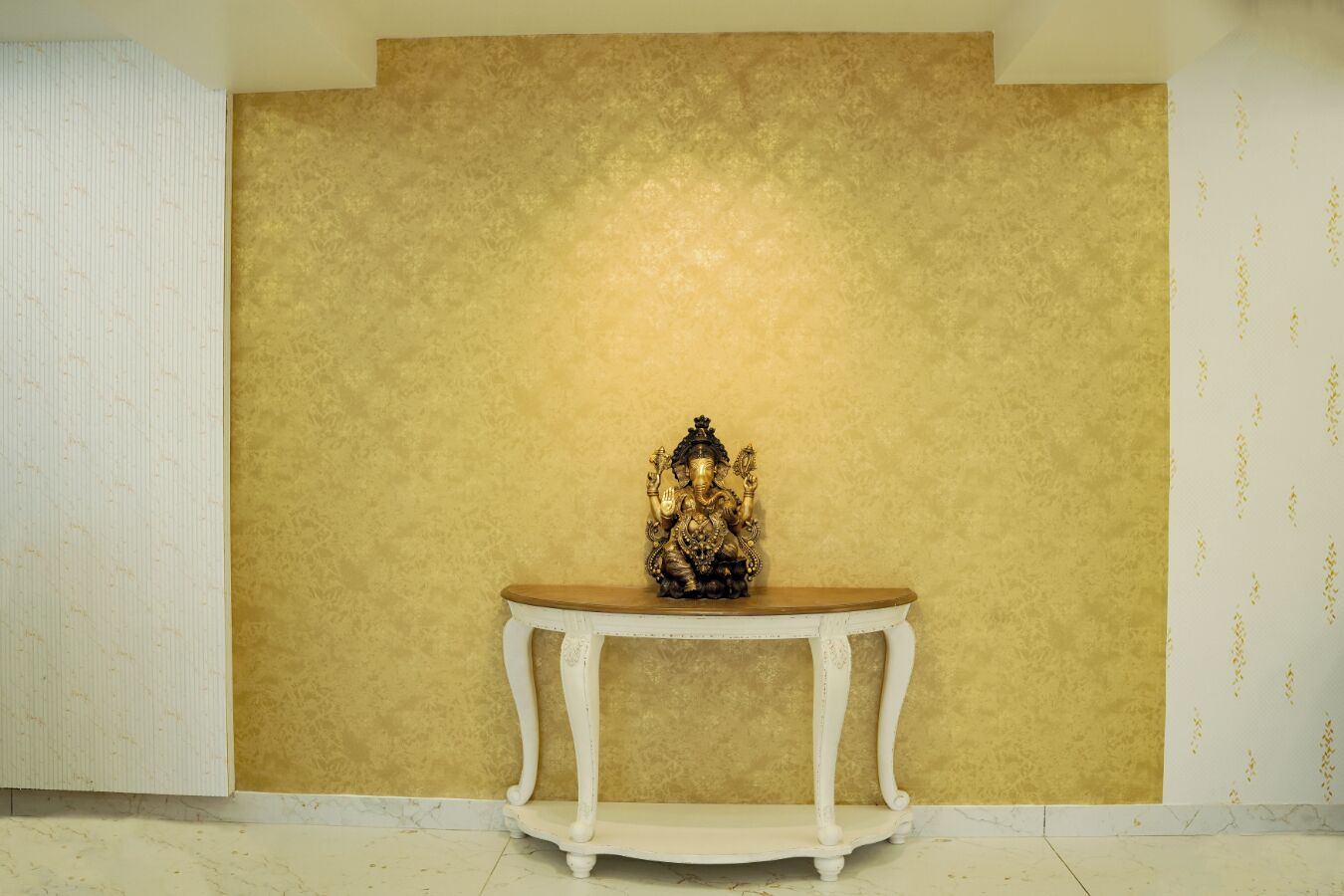 A statue on a white table against a textured wall.