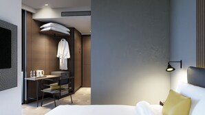 A modern hotel room with a bed, bedside table, and a desk with a chair. - Beezie Hotel (Palembang)