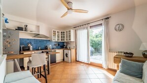 A compact kitchen with a ceiling fan, a washing machine, and a dining area with a table and chairs.