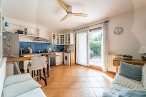 A compact kitchen with a ceiling fan, a washing machine, and a dining area with a table and chairs.