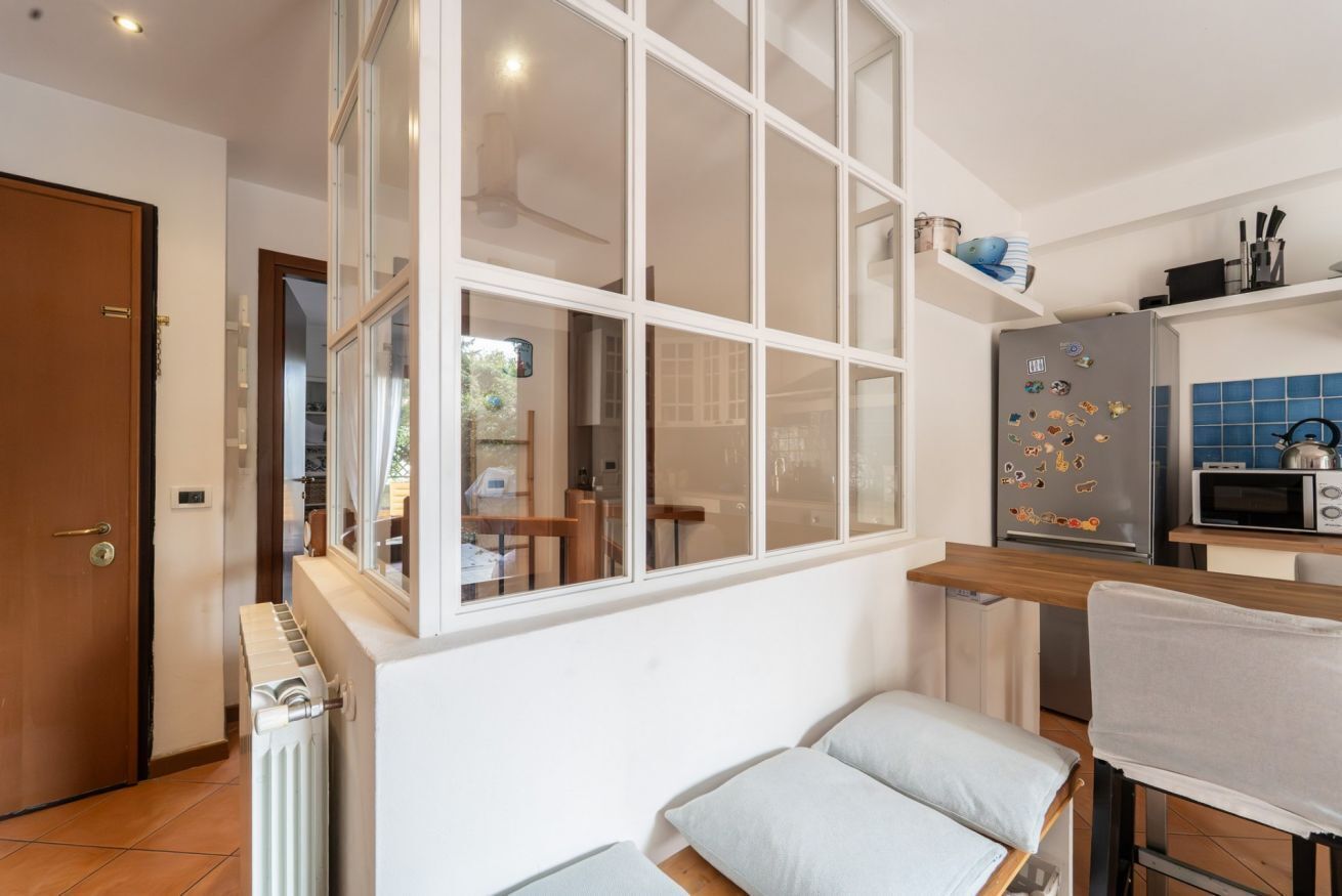 Eine kompakte Küche mit integriertem Kühlschrank, einer Mikrowelle und einem Fenster mit Blick auf den Garten.