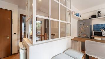 Eine kompakte Küche mit integriertem Kühlschrank, einer Mikrowelle und einem Fenster mit Blick auf den Garten.