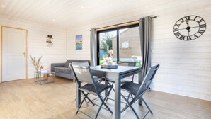 Un intérieur moderne avec une table à manger, des chaises, un canapé, une horloge et une vue par la fenêtre.