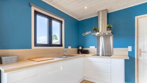 Une cuisine moderne avec des armoires blanches, une hotte de cuisinière en acier inoxydable, une fenêtre et une enseigne indiquant « Cuisine ».