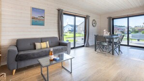 Un salon moderne avec un canapé gris, une table basse en verre et un coin repas comprenant une table et des chaises.