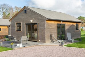 Ein modernes Haus mit einer Terrasse, Sitzgelegenheiten im Freien und einer großen Schiebetür.