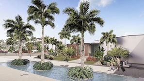 Un área ajardinada con palmeras, una fuente de agua y un edificio moderno con amplios ventanales.